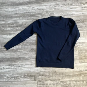 Mörkblå stickad tröja - Säljer en stilren mörkblå stickad tröja med rund hals och långa ärmar. Perfekt för kyligare dagar och enkel att matcha med olika outfits. M/S