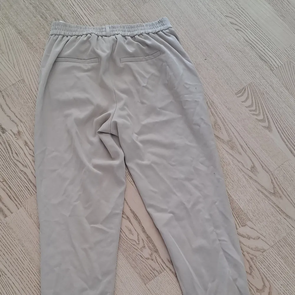 Snygga beige byxor med resårmidja och stilrena fickor. Perfekta för en avslappnad look. Byxorna har en enkel design med raka ben och är gjorda i ett mjukt material för extra komfort. (Linneblandning) . Farkut & Housut.