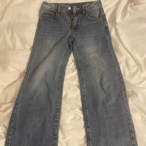 Blå jeansbyxor - Snygga blå jeansbyxor med en klassisk design. De har en rak passform och är perfekta för en avslappnad stil. Byxorna har fem fickor och stängs med dragkedja och knapp.