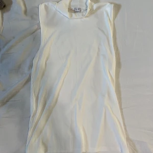 Vit ärmlös topp från new yorker - Säljer denna vita ribbade och ärmlösa toppen från new Yorker. Hög krage och lång i längden. Storlek L men passar som en S/M