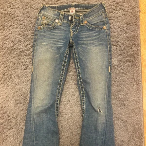 Blå jeans från True Religion - Snygga blå jeans från True Religion med slitna detaljer och kontrastsömmar. De har en bootcut-stil och låg midja🤍🤍🤍 säljer eftersom de är en aning korta på mig som är 172‼️