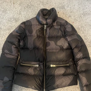 Jacka SOS Black Snow - Jacka från märket SOS Black Snow med fickor på framsidan. Den är militärmönstrad/ melerad och i strl 40 utifrån lappen, men jag är en XS/S, 162 lång och den sitter precis som den ska. Vet ej om just denna finns att köpa längre då den är äldre design! Sparsamt använd 🫶🏼