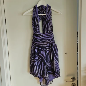 Lila zebramönstrad jumpsuit  - Snygg lila jumpsuit med zebramönster och knytband i nacken. Den har en unik design med omlott och öppen rygg som ger en trendig look.