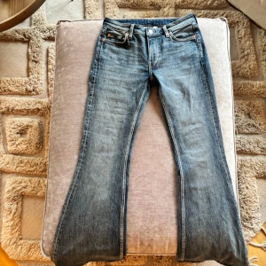 Blå bootcut jeans Weekday Flame - Snygga blå bootcut jeans från Weekday med klassisk femficksdesign och knappgylf. Perfekta för en avslappnad stil med en touch av retro. Passar bra till både sneakers och boots.