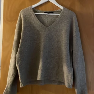 Beige stickad tröja med v-ringning - Säljer en mysig beige stickad tröja med v-ringning. Tröjan har långa ärmar och en avslappnad passform. Den är också lite nopprig och väl använd 