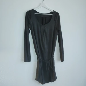 Svart klänning från Zara Basic - Snygg svart klänning från Zara Basic med långärmad design och rund hals. Klänningen har en enkel och stilren look med ett knytband i midjan för en smickrande passform. Perfekt för en chic och minimalistisk stil.