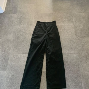 Svarta kostymbyxor  från Lindex - Snygga svarta byxor från Lindex med hög midja och vida ben. Perfekta för en stilren look. Tillverkade i ett bekvämt material som ger en elegant passform.