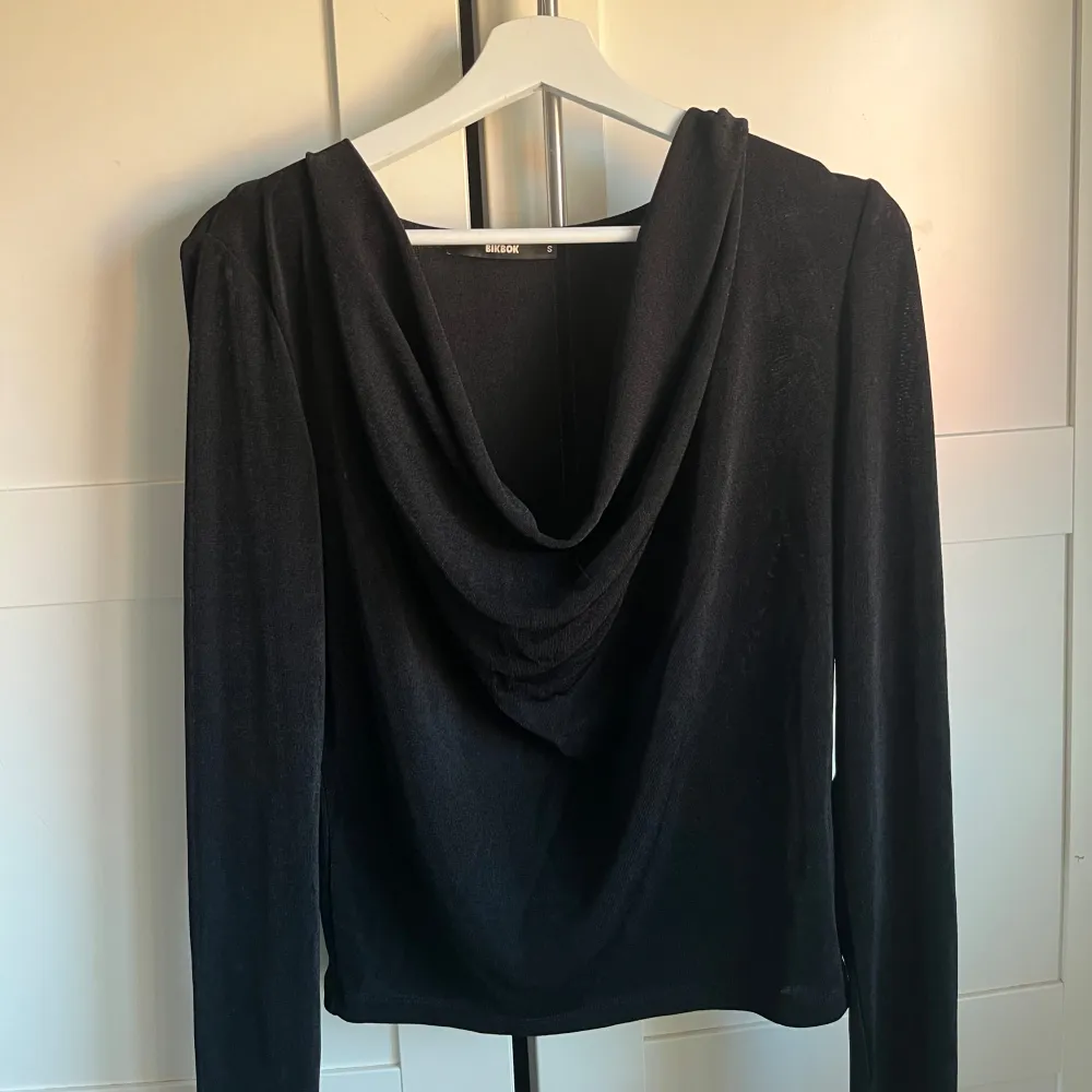 Snygg svart långärmad topp från BikBok med draperad halsringning. Perfekt för en stilren look. 🖤. Neuletakit & Villapaidat.