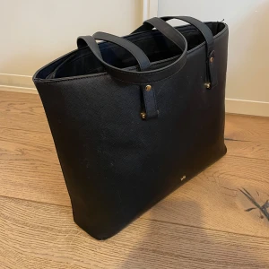 Svart väska🖤 - En svart väska som rymmer mycket. Den har ett mindre fack innanför och två handtag. I bottnet och i ena handtaget kan man se att den är lite sliten. Priset går att diskutera.