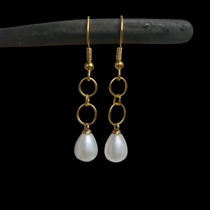 Guldiga örhängen med pärldroppar - Snygga örhängen med guldfärgade ringar och droppformade vita pärlor. De har en cool kedjedesign som ger ett trendigt intryck och passar perfekt för dig som gillar att sticka ut med dina accessoarer. Innehåller nickel, säljs i par. 
