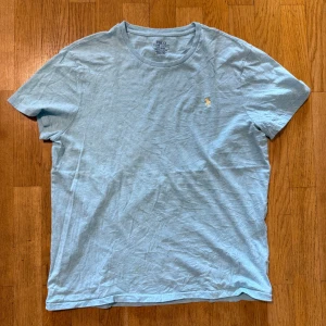 Ljusblå t-shirt från Polo Ralph Lauren - Snygg ljusblå t-shirt från Polo Ralph Lauren med klassisk rund hals och broderad logga på bröstet. Modellen är slim fit och tillverkad i mjuk bomull, perfekt för en clean och stilren look.