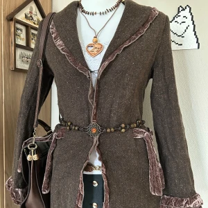 Vintage cardigan - Snygg brun cardigan med sammetsdetaljer längs krage, ärmslut och fickor. Materialet är ullblandning med mjuk känsla och klassisk look. Perfekt för dig som gillar vintage kläder med unika detaljer.