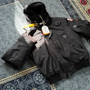 Svart Parajumper Dunjacka - Riktig skön svart dunjacka från Parajumpers med  detaljer som patch på ärmen, flera fickor och gul rem vid kragen och på baksidan. Jackan har quiltat foder, dragkedja och ribbade muddar. Perfekt för kalla dagar och riktigt snygg streetstil. Köpte på NK, nypris ligger på 10.499kr. Aldrig använt - bara testat. Det är en dubbeljacka med fler fickor både utanför, på armen och inuti.