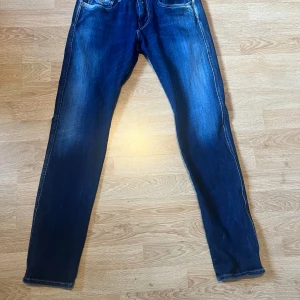 Replay Hyperflex jeans blå W31 L34 - Säljer ett par Replay Hyperflex jeans i klassisk blå tvätt. Jeansen har raka ben, fem fickor och snygga slitningar framtill. Materialet är stretchigt för extra komfort och passformen är normal. Perfekta för dig som gillar stilrena och bekväma jeans.
