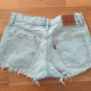 Levi's ljusblå jeansshorts  - Säljer ett par så snygga och ikoniska Levi’s 501 premium jeansshorts i ljusblå denim, med klassisk knappgylf och rå fransig kant nedtill. Använda en gång 2023 annars är dom i super fint skick. Dock är det något svart på ena fickan, antagligen från när jag reste med dom i resväskan men är inget som är så tydligt och synligt!! Säljer pga att dom tyvärr inte passar mig längre. Det står ingen strl på dom men skulle gissa runt 34/36. 