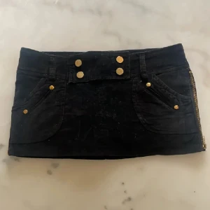 Coolaste kjolen wowsiiiii❤️ - Supersnygg svart kortkjol i mjuk manchester med coola guldknappar och dragkedjor i sidorna som man kan öppna. Fickor både fram och bak ger en chill vibe. Perfekt för dig som vill sticka ut lite extra! Kjolen har bälteshällor och sitter tajt men bekvämt. Superkort men shorts under❤️ Supersnygga❤️ midjemått ca 40 cm