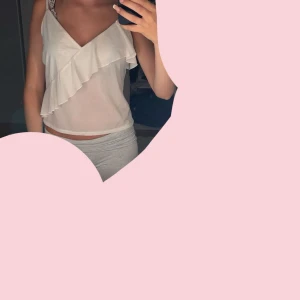 Vit linnetopp med volang - Säljer en söt vit linnetopp med v-ringning och volangdetalj framtill. Toppen är ärmlös och har en luftig känsla, perfekt för varma dagar. Enkel att matcha med både jeans och kjol.