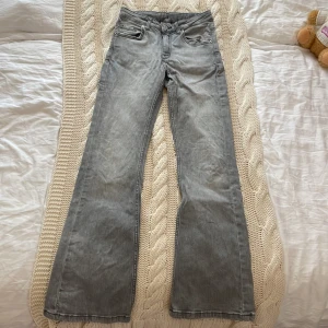 Grå bootcut jeans i stl 146 - grå jeans med bootcut-modell och klassisk femficksdesign. Jeansen har normal passform och är tillverkade i mjukt denimtyg. Byxorna har spruckit lite där bak men är inget som man ser.