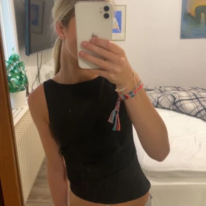 Svart ärmlös topp från Gina Tricot - Säljer denna svarta lite mer fest toppen, använd 1 gång och den är kort på ena sidan och fortsätter och blir längre till den andra sidan