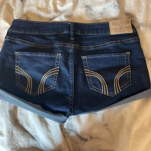Mörkblå jeansshorts från Hollister - Man kan välja hur mycket man vill vika upp eller klippa av dom mer. Snygga mörkblå jeansshorts från Hollister. Ca 34 cm i midjemått. Shortsen är köpta från Plick och men aldrig andvända. 💕 Skriv om ni vill ha bättre bilder eller mått och sånt💗jag vek upp dom ganska slarvigt men man kan vika hur man vill✌🏼