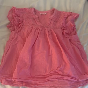 Rosa volangblus med v-ringning   - Supersöt rosa blus med v-ringning från Gina, passar perfekt nu på sommaren men även när som helst!💞Den är lätt att styla till exempel med ett par jeans eller varför inte en kjol?😍 Säljer i storlek 170, pris kan gärna diskuteras💞