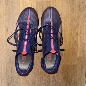 Puma Ultra Ultimate - Säljer ett par Puma Ultra fotbollsskor i lila med röda och vita detaljer. Köpt för 2500 kr. Använda 5 gånger.