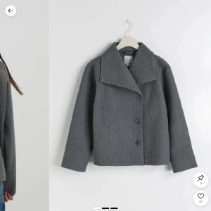 Gina Young grå kappa - Snygg grå rock med bred krage och stora knappar framtill. Jackan har en boxig passform och är tillverkad i ull, perfekt för kyliga dagar. Stilren och enkel att matcha med olika outfits.