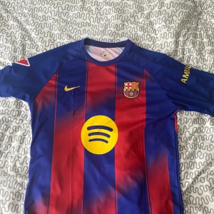 FC Barcelona Lamine Yamal 10 Nike tröja - Barça matchtröja med Lamine Yamal 10 på ryggen. Klassiska blå och röda ränder, gula detaljer och broderat klubbmärke. Nike-logga på bröstet, Spotify och UNHCR-tryck. Kan gå ner lite om de skulle behövas 