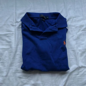 Blå polo piké  - Säljer denna Ralph polo pike för att den är för liten. Har använts lite men syns knappast. 