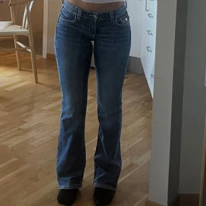 Blå bootcut jeans med broderade fickor - Snygga blå bootcut jeans med broderade bakfickor och knappdetalj. Jeansen har låg midja.  Jag är 170 och dom är perfekt längd på mig. Använd fåtal gånger. 