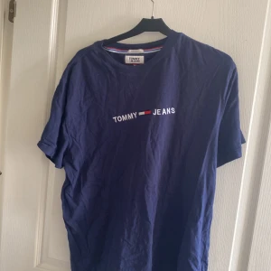 Marinblå t-shirt från Tommy Jeans - Snygg marinblå t-shirt från Tommy Jeans med klassisk logga broderad på bröstet. Regular fit och rund halsringning. Perfekt basic-plagg med cool streetkänsla och skön bomullskvalitet.