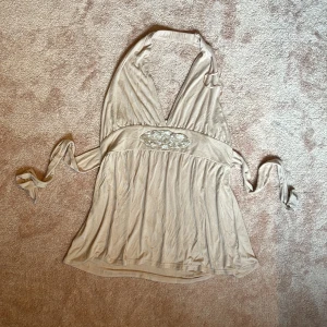 Beige lång halterneck topp med pärldetalj H&M🥂💋 - 🥂💋Supersnygg och lyxig beige (med rosa ton) halterneck topp från H&M med knyt i midjan  och halvt öppen rygg. Kkulle kunnat haft som klänning om man är något kortare och/eller har mindre storlek än L.  Den har en djup v-ringning och är dekorerad med  pärlor framtill. Tillverkad i mjukt, tunt och elastiskt material som faller snyggt. Passar superbra till fester om man vill känna sig lite extra uppiffad! 🥂🪩💋🐆OBS, det finns katter i huset