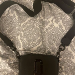 Marc jacobs Snapshot - Säljer min fina marc jacobs snapshot bag. Den är väldigt praktisk att ha med sig ut, man får plats med mobil,nycklar plånbok och favvo läppglanset😊 Som ni ser så saknas själva ”kroken” till dragkedjorna. Men väskan går självklart att öppna ändå. Nypris ca 4400kr🫶🏼