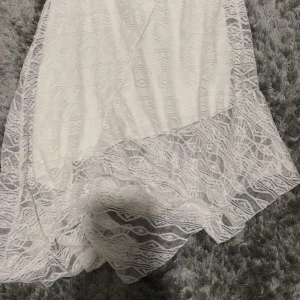 Vit spetskjol från Gina Tricot XS - Supersöt vit kortkjol från Gina Tricot i storlek XS. Kjolen har ett lager av spets med snyggt mönster och en volangkant nertill som ger extra flow. Perfekt för dig som vill ha en feminin och trendig look.