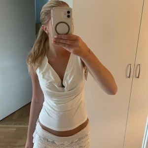 Jättefin vit topp (helt ny) - Säljer en helt ny vit topp i mjukt material med snygg drapering framtill från Gina tricot. Toppen är ärmlös och har en croppad passform som passar perfekt till sommaren. Enkel att styla med både jeans och kjol. Köpt för 259kr men säljer för 199!
