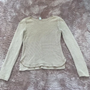 Beige stickad tröja från Vila - En stilren beige stickad tröja från Vila i storlek S. Tröjan har rund halsringning, långa ärmar och ribbade muddar samt nederkant. Perfekt för lager-på-lager och enkel att matcha med jeans eller kjol.