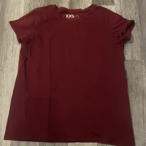 Mörkröd t-shirt från FSBN Sister - En enkel och stilren mörkröd t-shirt från FSBN Sister. T-shirten har rund halsringning och korta ärmar, perfekt för en avslappnad look. Tillverkad i mjuk bomull för skön komfort.