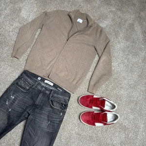 Beige ziptröja från NN07 - Säljer en stilren beige ziptröja från NN07. Tröjan har hög krage och dragkedja hela vägen framtill. Storlek M, köp för endast 399.