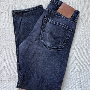 Svarta Levi's 501 jeans - Klassiska svarta Levi's 501 jeans med raka ben och fem fickor. Jeansen har knappgylf och är tillverkade i slitstarkt denim. Perfekta för dig som gillar en tidlös och avslappnad stil.