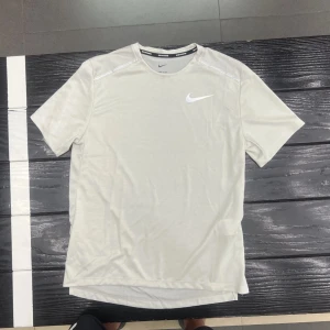 Grå sportig t-shirt från Nike - Säljer en grå t-shirt från Nike med klassisk logga på bröstet. T-shirten har korta ärmar och är tillverkad i ett lätt och syntetiskt material som passar perfekt för träning eller sportaktiviteter. Storlek S men har andra storlek ocsk, skick 10/10.
