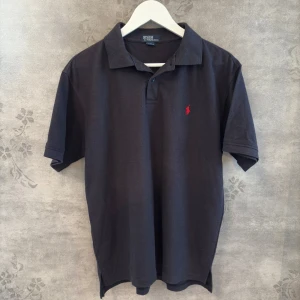 Ralph Lauren piké - Stilren klassiker i svart från Ralph Lauren. Ikonisk röd logga på bröstet, snygg passform och ett tidlöst plagg som alltid är rätt.  Ralph Lauren, Polo Ralph Lauren, Pikétröja herr, Preppy stil, Klassisk piké, Designer piké, Streetwear, Herrmode, Loggopiké, Sommarstil, Snygg piké, Trendigt plagg.  #ralphlauren #svartpiké #herrmode #pikétröja #preppy #streetwear #polo  Storlek: L Skick: Väldigt bra - inga fläckar eller hål Nypris: ca 999 kr  Pris: 250 kr (kan diskuteras vid snabb affär)