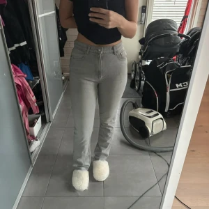 Ljusgrå jeansbyxor med normal passform - Säljer ett par ljusgrå jeansbyxor med klassisk femficksdesign och normal passform. Byxorna har hög midja och raka ben, perfekta för en stilren vardagslook. Passar dig som gillar enkel och tidlös stil.