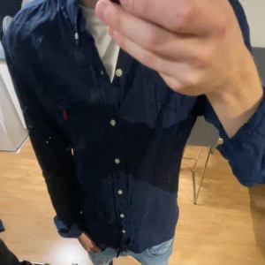 Mörkblå linne skjorta från Polo Ralph Lauren - Säljer en mörkblå linne skjorta från Polo Ralph Lauren i slim fit. Klassisk design med knappar hela vägen och liten broderad logga på bröstet. Perfekt för dig som gillar stilrena plagg med snygg passform. Köpt för 2000kr och är i mycket bra skick. Skriv vid frågor eller diskution av pris!