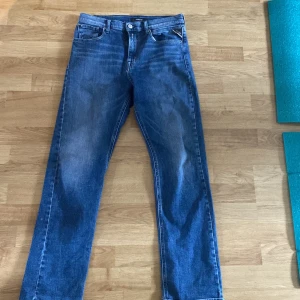 Blå jeansbyxor från Replay - Säljer ett par klassiska blå jeans från Replay Thad med raka ben och normal passform. Byxorna har fem fickor, knappgylf och tydliga Replay-detaljer vid linningen. Perfekta för dig som gillar en tidlös jeansstil. Aldrig andvändt dem säljer för 200kr står inte storleken bara längden 166cm
