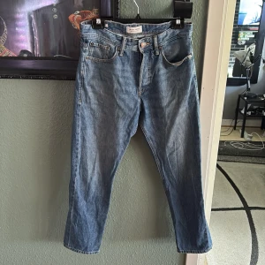 Blå jeans från Jack & Jones Loose/Chris - Säljer ett par klassiska blå jeans från Jack & Jones i modellen Loose/Chris. Jeansen har fem fickor, knappgylf och en lösare passform med raka ben. Perfekta för dig som gillar en avslappnad stil.