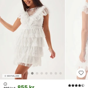 Vit spetsklänning med volanger - Superfin vit kortklänning i spets med flera lager volanger och v-ringning i ryggen. Perfekt för somriga tillfällen eller student.