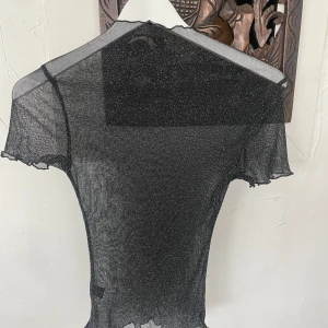 Svart spetsig bralette med tunna axelband - Säljer en svart bralette med vackra spetsdetaljer och tunna axelband. Toppen har blommigt spetsmönster och en croppad passform, perfekt att styla under en transparent topp eller som den är. Tröjorna säljs ihop.