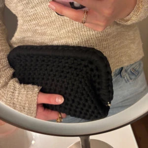 Svart handvirkad clutch / väska - Säljer en svart handvirkad clutch / handväska som jag har virkat! Väskan är i ett mjukt garn och är väldigt rymlig! Kan bäras i handen som en clutch eller bäras i handtaget.  Kan Även Göra Andra Färger / storlekar💕 skriv för mått, olika på vissa 💕