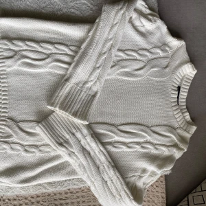 Vit kabelstickad tröja - Säljer en vit kabelstickad tröja från Lager 157 i storlek S. Tröjan har ett klassiskt flätmönster, rund halsringning och långa ärmar med breda muddar. Använd ca 2-3 gånger. 