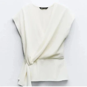 Vit omlottopp med knyt från Zara - Säljer en stilren vit omlottopp från Zara med knyt i sidan. Toppen har korta ärmar och en elegant v-ringning. Den är använd endast vid ett tillfälle🩷         Tog denna bild enbart för la ut snabbt, fråga gärna om bilder privat💕